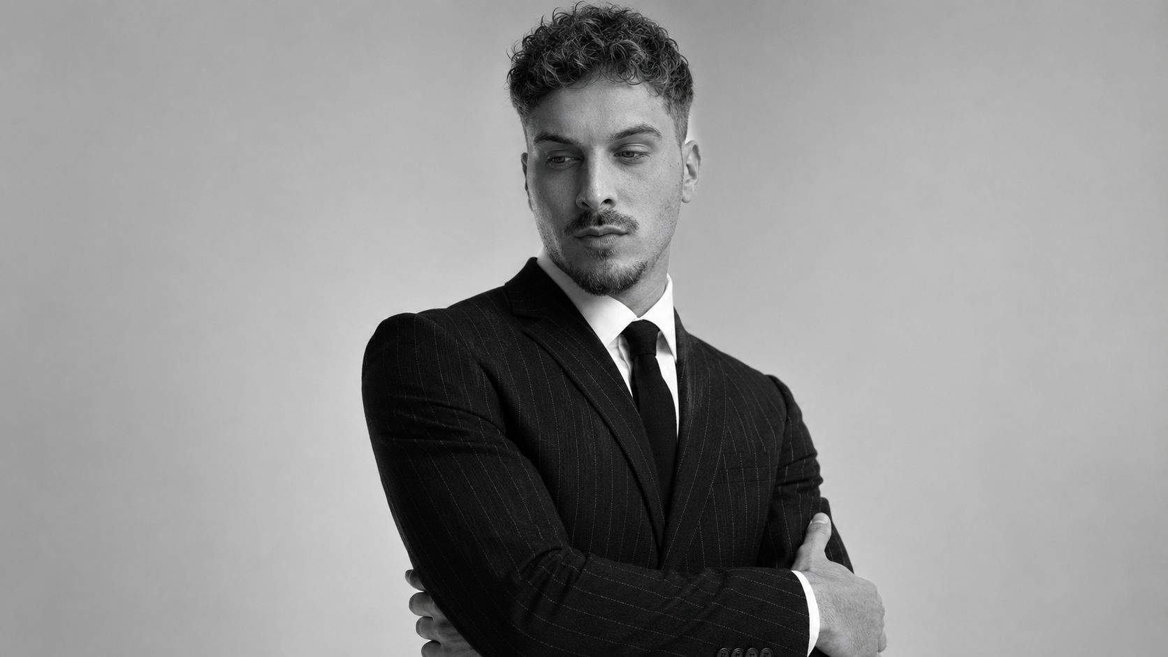 Retrato editorial de Ángel Garrido en blanco y negro, traje oscuro, brazos cruzados.